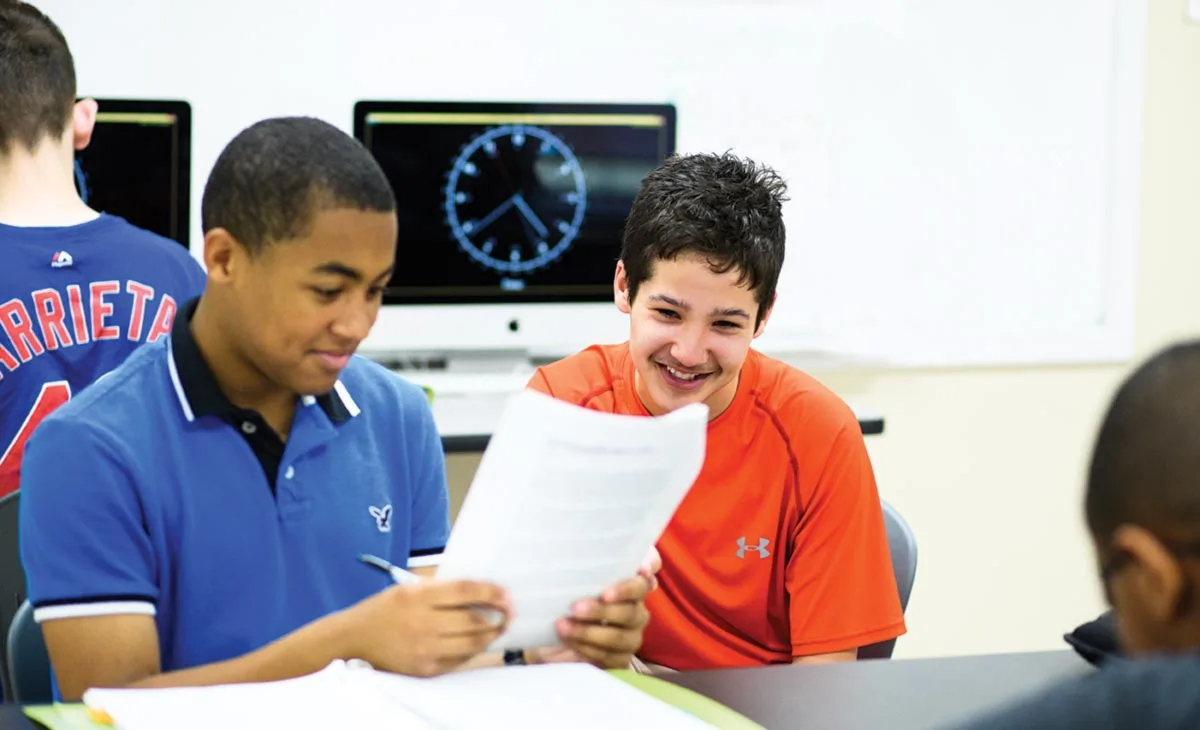 Teacher guiding a student with personalized support during a classroom activity, fostering independence at OPTIONS Transitions to Independence.