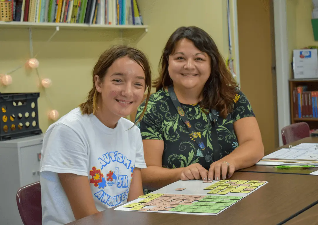 Teacher guiding a student with personalized support during a classroom activity, fostering independence at OPTIONS Transitions to Independence.